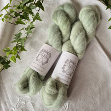 Load image into Gallery viewer, Two skeins of light green yarn with labels on a textured surface with plants in the background