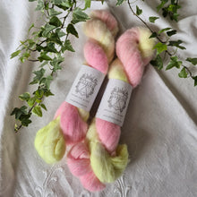 Load image into Gallery viewer, Two skeins of pink and yellow yarn with labels on a textured fabric background