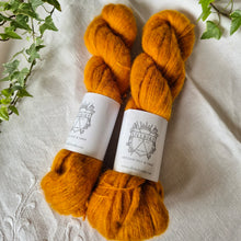 Load image into Gallery viewer, Two skeins of golden yellow yarn with labels on a textured fabric background